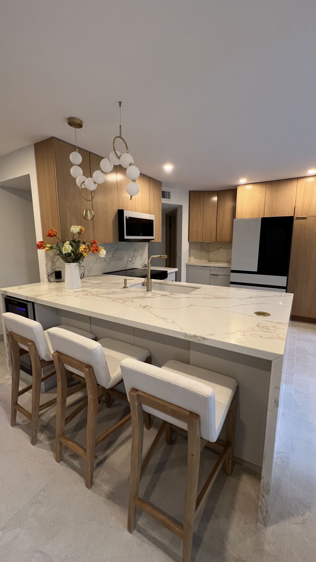 Open kitchen with marble waterfall island and orb chandelier