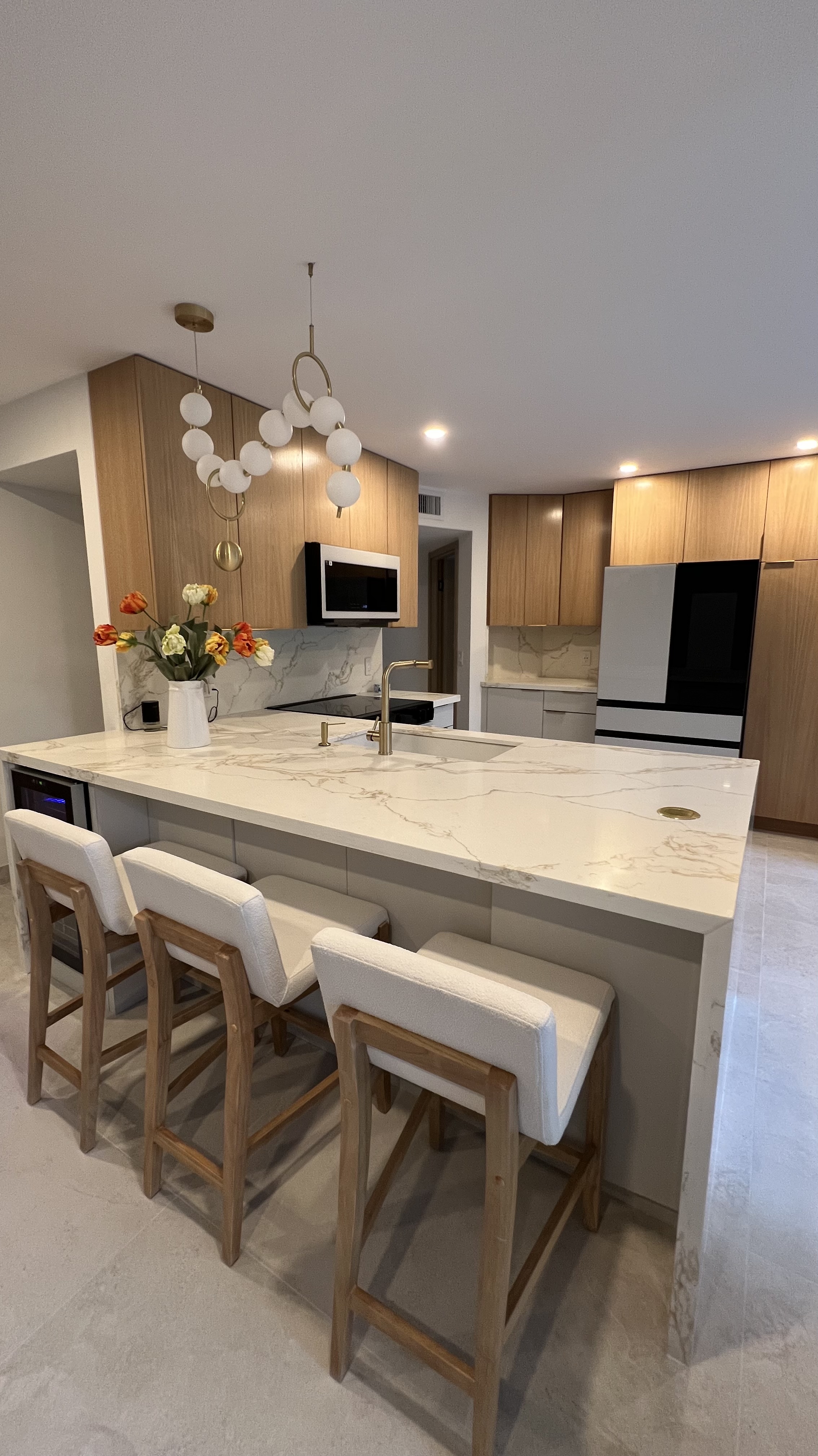 Open kitchen with marble waterfall island and orb chandelier